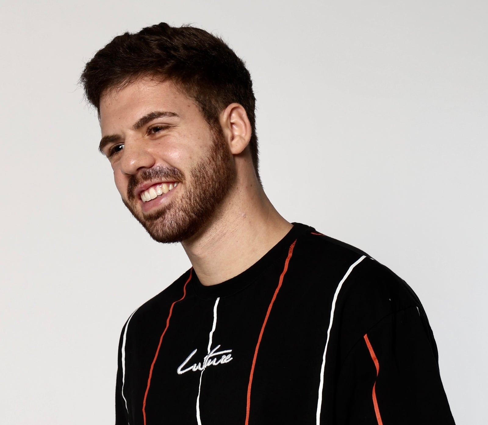 Man wearing a black shirt with red and white accents on a light gray background